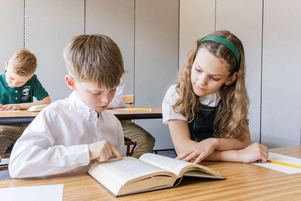 Two students read together at their desks