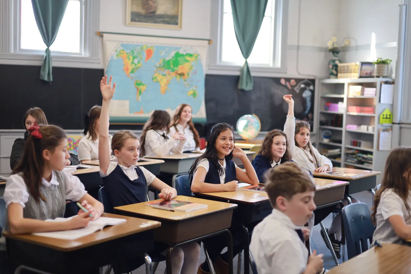Students raise their hands to answer during a classroom lesson