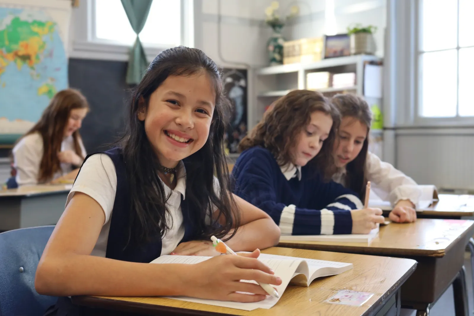 A student smiles at her desk during class