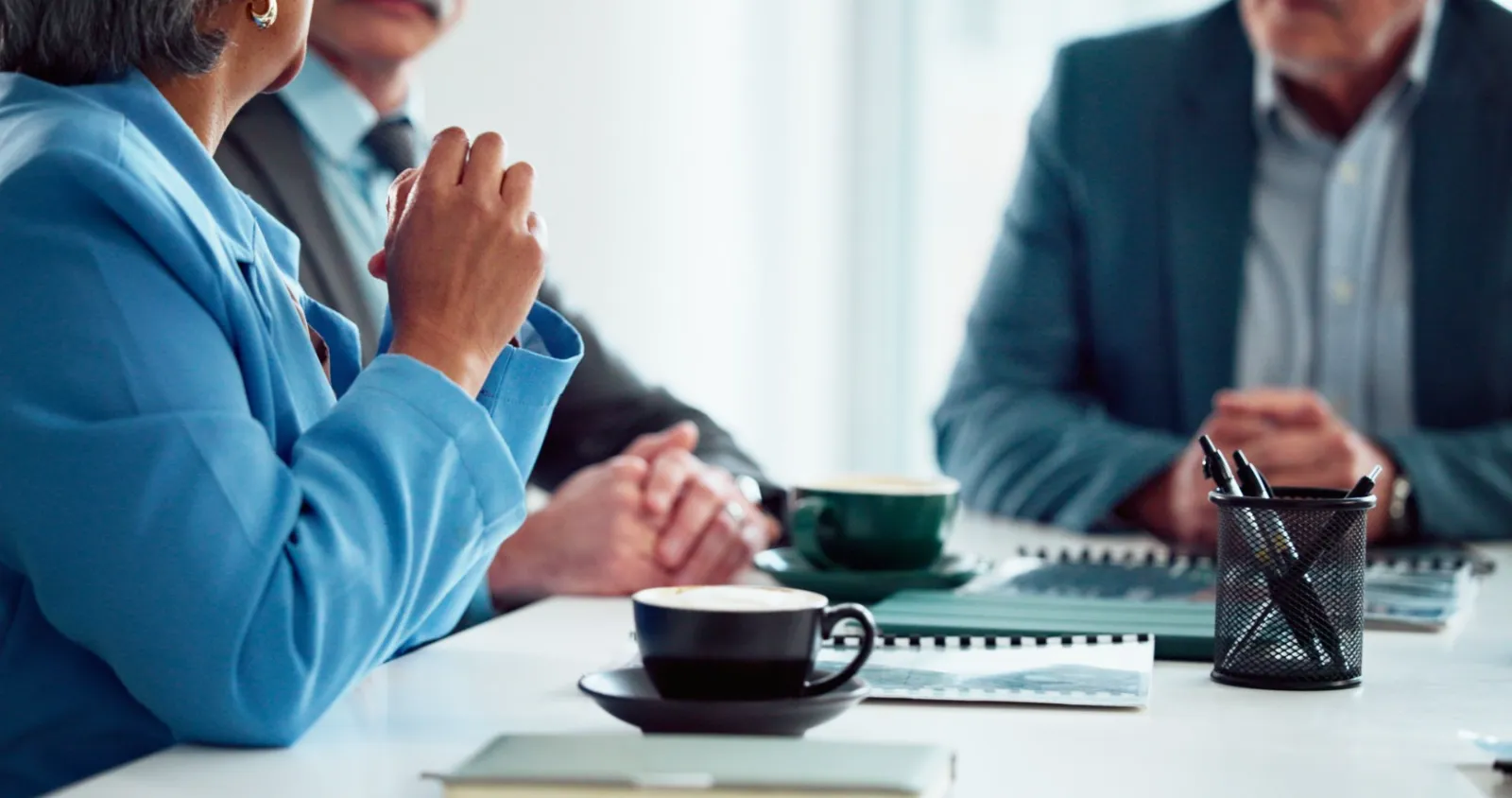 Board members meet around a table with coffee and notes