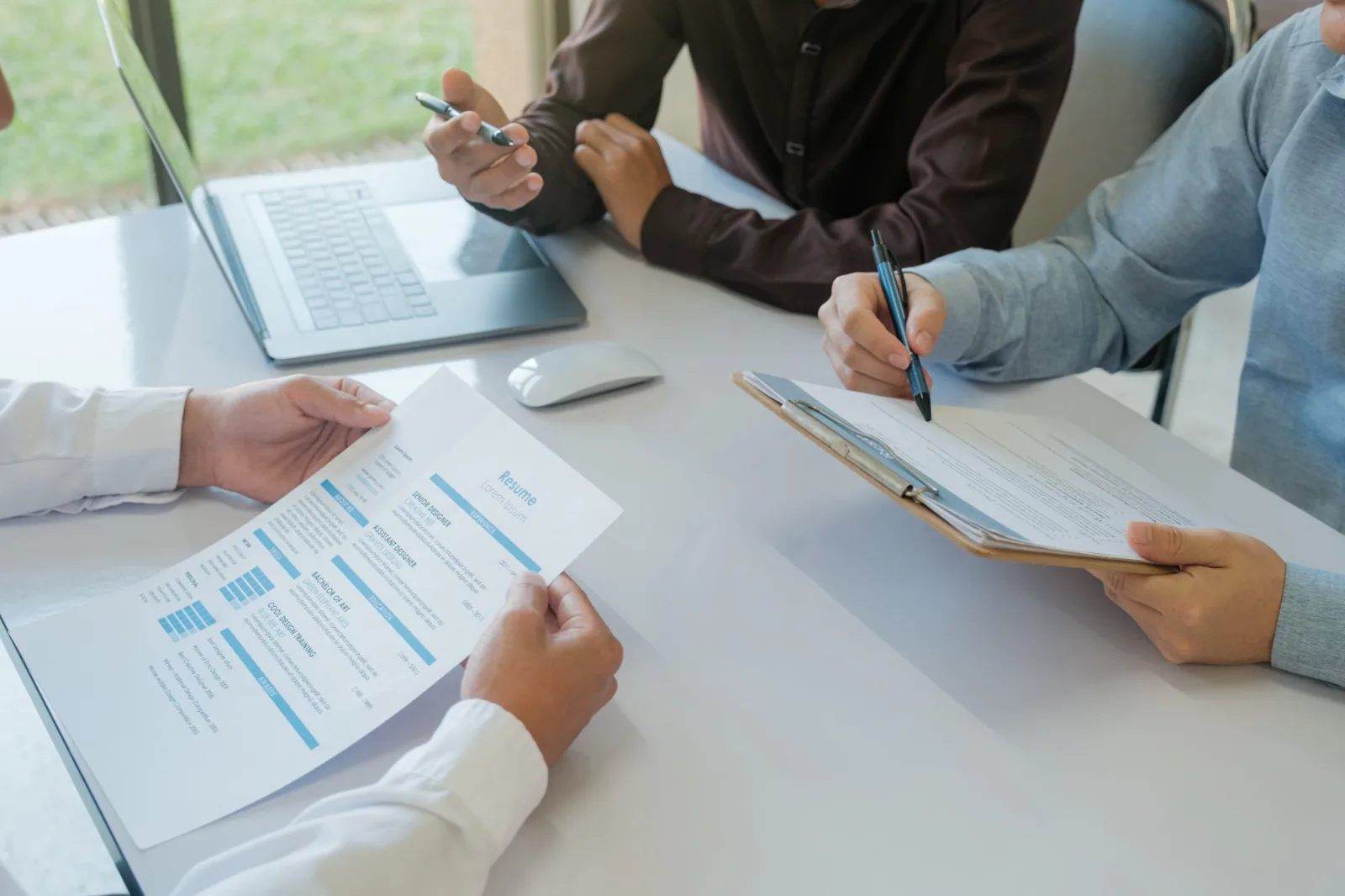 Hands reviewing a résumé and notes during an interview at a table