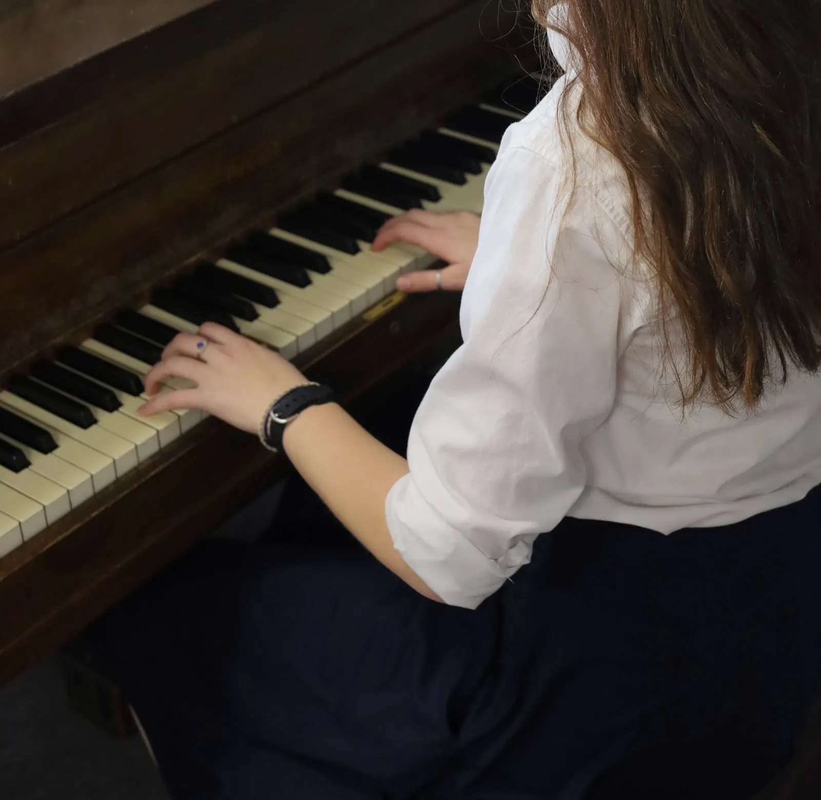 A student’s hands rest on piano keys during a lesson
