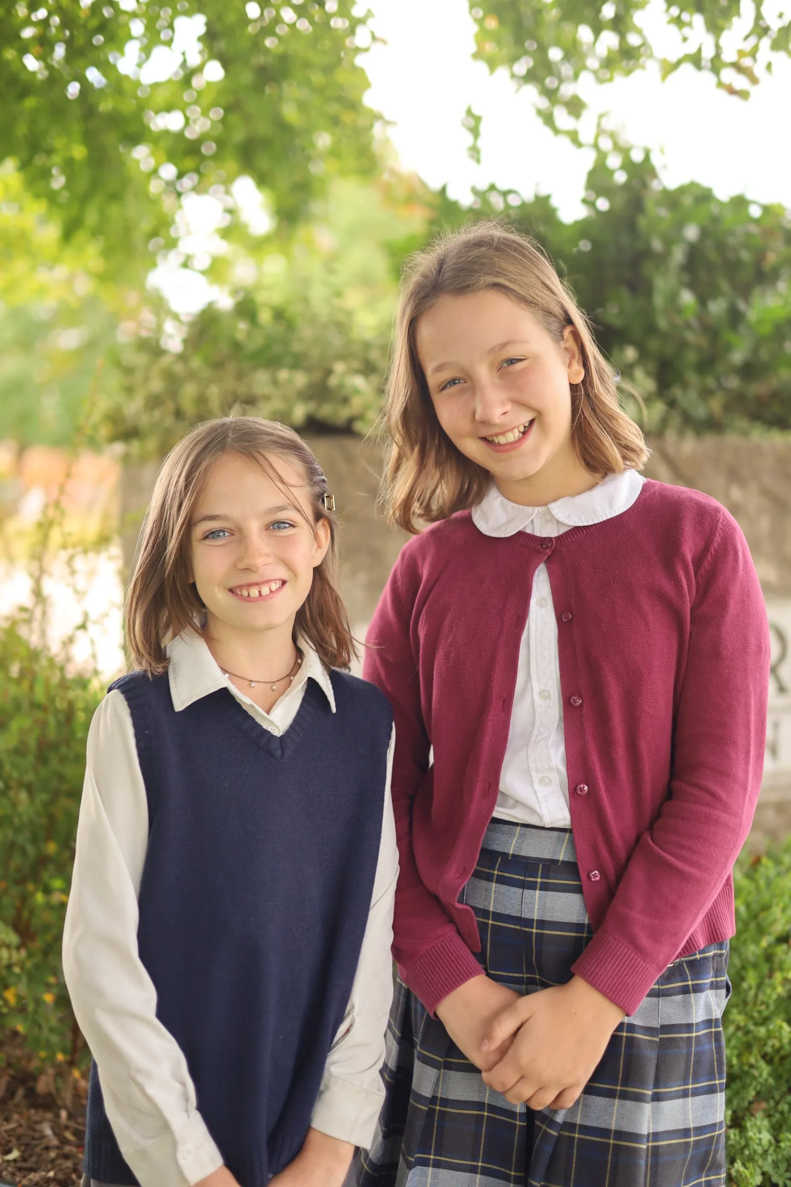 Two students in school uniform stand side by side outdoors